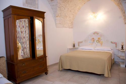 Schlafzimmer mit einem Bett, einer Kommode und einem Spiegel in der Unterkunft Casa del Carbonaio in Locorotondo