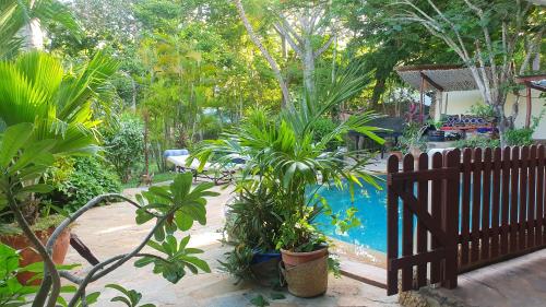 a garden with a fence and plants and a swimming pool at Mami Wata House in Kwale