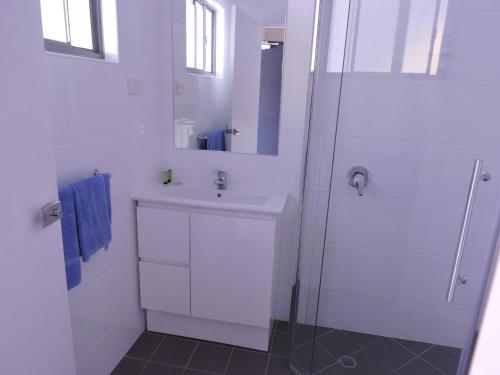 a white bathroom with a sink and a shower at Siesta Villa in Jindabyne