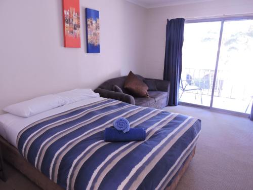 a bedroom with a bed with a blue towel on it at Siesta Villa in Jindabyne