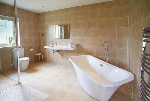 uma casa de banho com uma banheira, um lavatório e um WC. em Ramson Lodge em Chappel