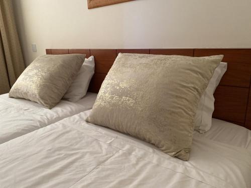 Una cama con dos almohadas encima. en BayView Albufeira, en Albufeira
