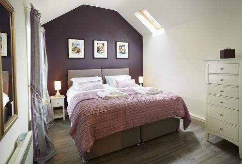 a bedroom with a bed with a purple wall at Mason's Cottage in Ampleforth