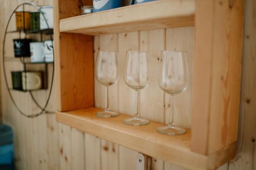 trois verres à vin assis sur une étagère dans une pièce dans l'établissement GLAMPING SLOVENSKO, à Konská