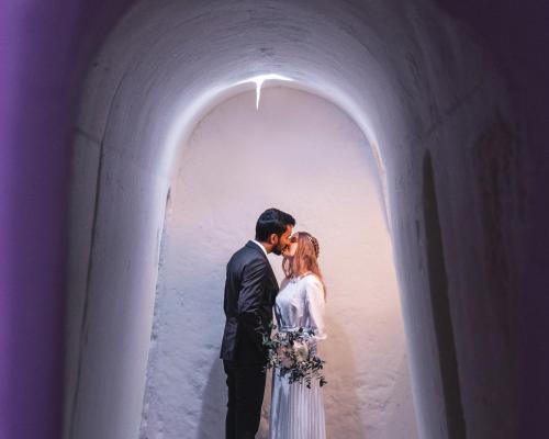 a bride and groom kissing in a tunnel at Arctic SnowHotel & Glass Igloos in Sinettä