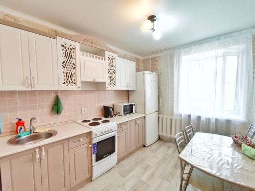 una cocina con electrodomésticos blancos y una mesa con comedor. en Люксовые апартаменты в Центре г.Семей, en Semey