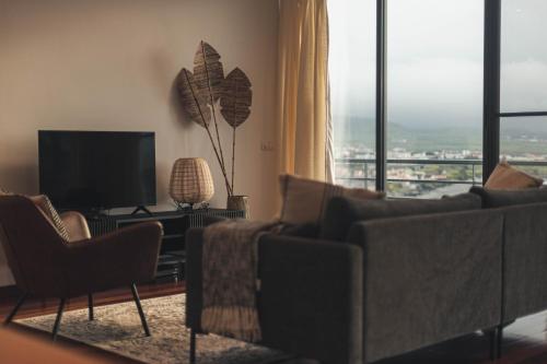a living room with couches and a flat screen tv at Ribeira Grande Ocean View Apartment in Ribeira Grande