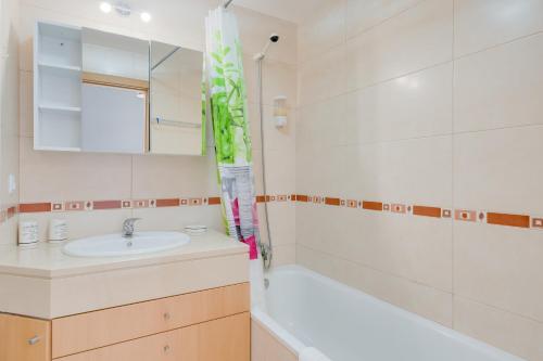 Un baño con lavabo, bañera y espejo. en Alta do Garajau II, en Caniço