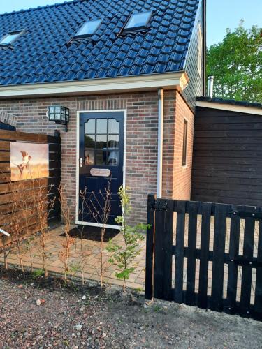 a house with a blue door and a fence at B&B De Boeren Zwaluw in Slochteren