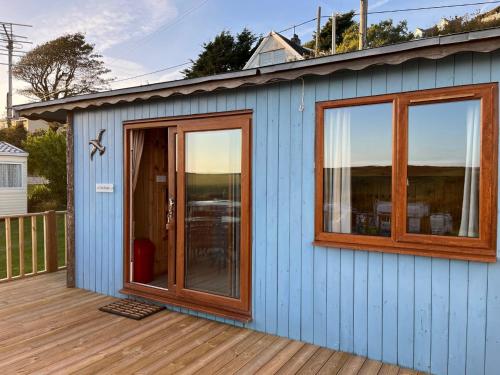 a blue house with windows and a deck at Cove Shepherds Hut in Penally