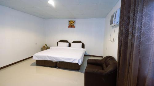 um quarto com uma cama e uma cadeira em The Palm Estate em Fujairah