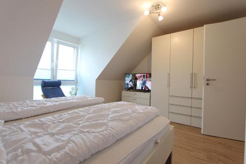 a white bedroom with a bed and a tv at Haus Kleine Brise in Kellenhusen