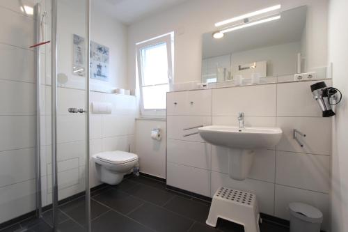 a white bathroom with a sink and a toilet at Haus Kleine Brise in Kellenhusen