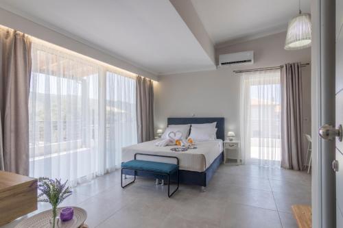 a bedroom with a bed with a blue stool and windows at Elite City Apartments & Maisonettes in Lefkada