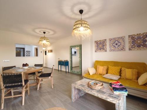 een woonkamer met een gele bank en een tafel bij Sunny Luxury Apartment with two great sunny - level terraces, two swimming pools, in a new complex Pueblo Majorero, close to Fuerteventura Golf Club, next to the beach , Atlantico Shopping Mall and casino in Caleta de Fuste in Caleta De Fuste