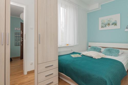 a bedroom with a bed with a green bedspread at Apartamenty NCNK Leśny Zaułek Sztutowo in Sztutowo