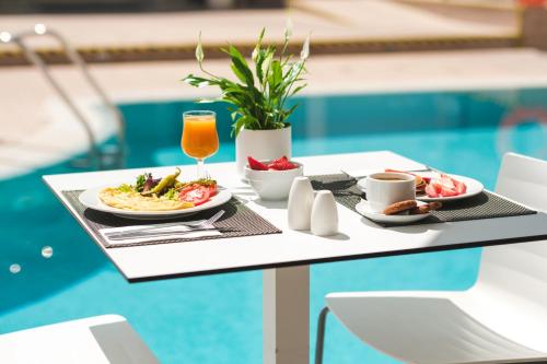 einen Tisch mit Speisen und Getränken auf einem Tisch am Pool in der Unterkunft Hotel Triton Beach in Cala Ratjada