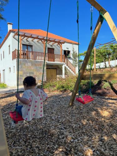 a little girl sitting on a swing at Casa Bizarra in Castanheira de Pêra