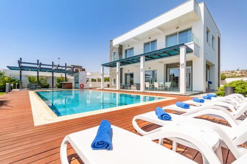 a swimming pool with white lounge chairs and a building at Villa Marsali by Ruidoso Luxury in Ayia Napa
