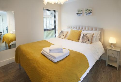 um quarto com uma grande cama branca e um cobertor amarelo em Mallow Lodge 6 em Bamburgh