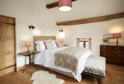 a bedroom with a large bed with a table and a dresser at The Longbarn at Caerfallen in Ruthin