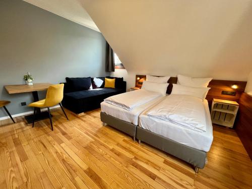1 dormitorio con 1 cama y 1 sofá en JUNIPRO Hotel Schinderhannes, en Weiskirchen