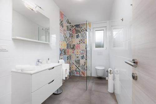 a white bathroom with a sink and a toilet at Apartment Mužini Malinska in Malinska