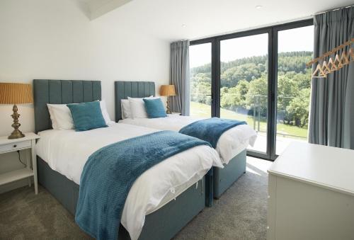 twee bedden in een kamer met een groot raam bij Teign Vale in Cheriton Bishop