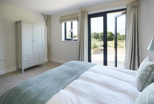 a bedroom with a large white bed and a window at Bokes Barn in Hawkhurst