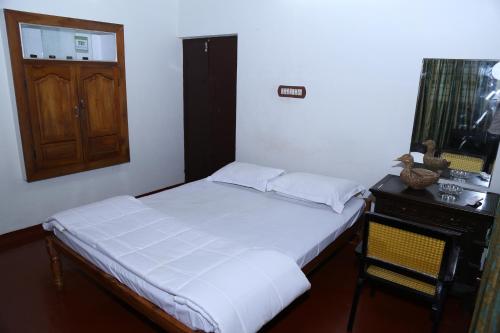 a bedroom with a bed and a table and a mirror at Aqualillies Water Front Heritage Homestay in Kumarakom