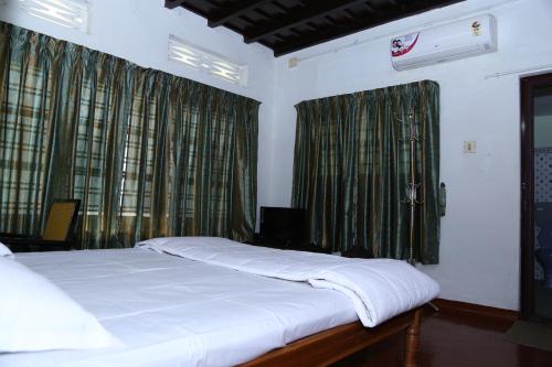 a bed in a bedroom with green curtains at Aqualillies Water Front Heritage Homestay in Kumarakom
