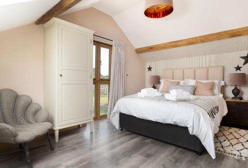 a bedroom with a large bed and a chair at The Timber Barn in Downton