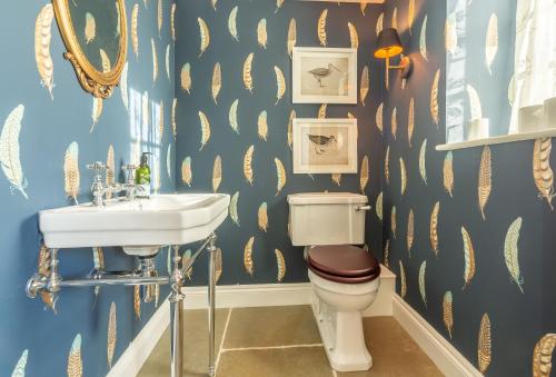 a bathroom with a sink and a toilet with gold leaf wallpaper at Bodney Lodge in Bodney