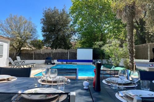 - une table avec des verres à vin à côté de la piscine dans l'établissement Villa des Pins - Piscine & proche de la plage, à Saint-Hilaire-de-Talmont