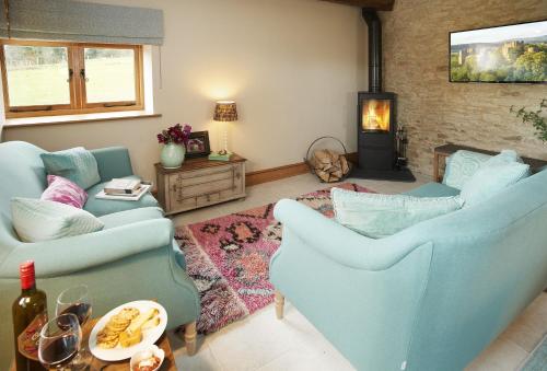 a living room with two blue chairs and a fireplace at The Stone Barn in Downton