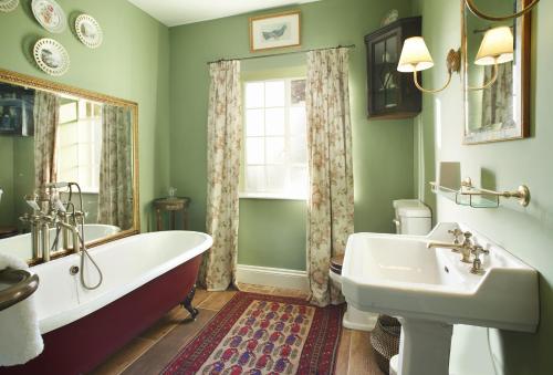 baño con bañera, lavabo y ventana en The Green, en Coneysthorpe