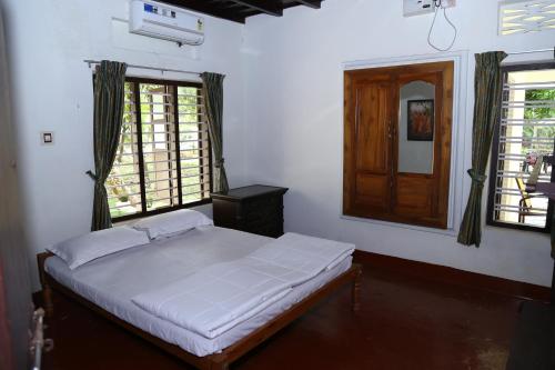 a bedroom with a bed in a room with windows at Aqualillies Water Front Heritage Homestay in Kumarakom