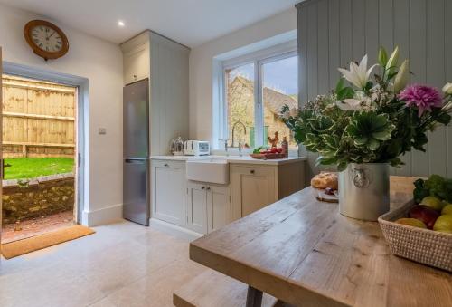 a kitchen with a table with a vase of flowers at 1 Church Cottages 