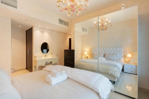 een witte slaapkamer met 2 bedden en een spiegel bij Downtown Dubai, Luxury 2 Bed 2 Bath Apartment - Pool, Gym, AirCon, Parking - Views of The Dubai Fountain & Burj Khalifa in Dubai