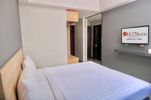 a bed in a room with a sign on the wall at @Hom Semarang Simpang Lima in Semarang