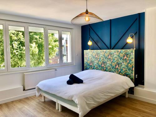 - une chambre dotée d'un lit avec un mur bleu et des fenêtres dans l'établissement COC - La Maison Des Secrets, à Calais