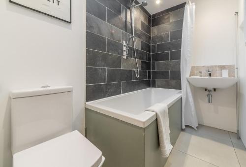 a bathroom with a tub and a toilet and a sink at The Garden Room in Westmeston