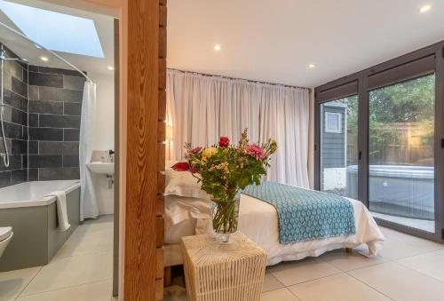 um quarto com uma cama e um vaso de flores em 1 Church Cottages & Garden Room 