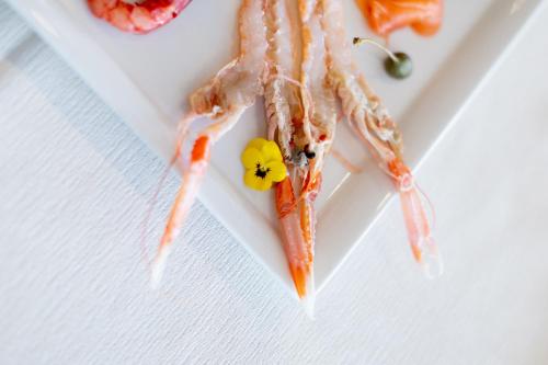 a plate of food with shrimp and a flower on it at Casa Merano Residence & Restaurant Bibione Centro in Bibione