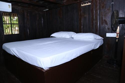 a bed with white sheets and pillows in a room at Aqualillies Water Front Heritage Homestay in Kumarakom