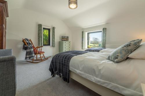 a bedroom with a bed and a chair and a window at Linden Barn in Orton