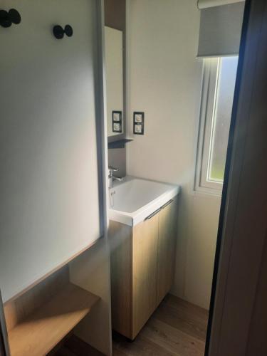une salle de bain avec un lavabo blanc et un miroir dans l'établissement Charmant mobil-home 178, à Narbonne