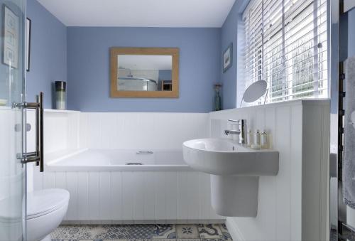 uma casa de banho com um lavatório, uma banheira e um WC. em Rock Cottage em Minchinhampton