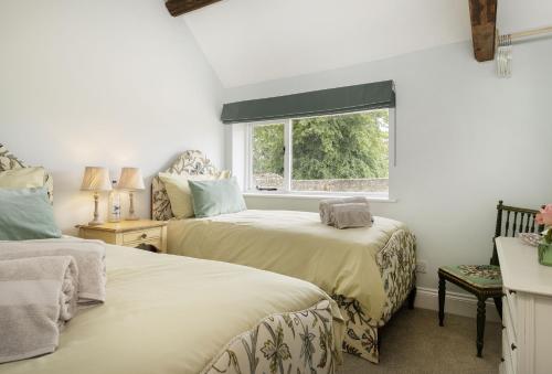 two beds in a room with a window at Long Barn in Coates