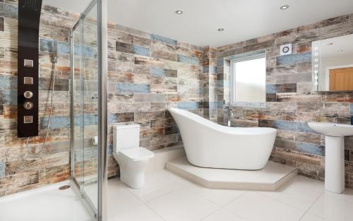 a bathroom with a tub and a toilet and a sink at Stunning 1-Bed Cottage near Carlisle with Hot tub in Carlisle